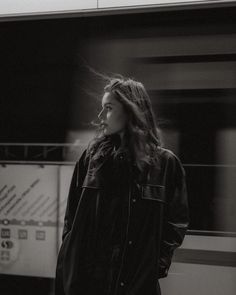 a black and white photo of a woman standing in front of a train