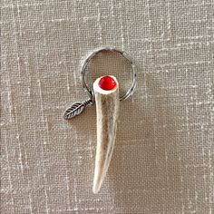 an animal's tooth with a red stone in the center on a silver ring