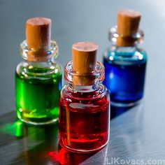 three different colored glass bottles sitting on top of a table