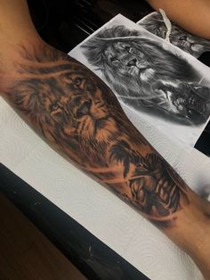 a man with a lion tattoo on his arm sitting next to a drawing and pencil