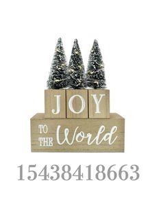 a wooden sign that says joy to the world and three small trees on top of it