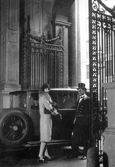 an old black and white photo of two women standing next to a car in front of a building