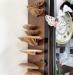 a clock mounted to the side of a wall with mushrooms on it