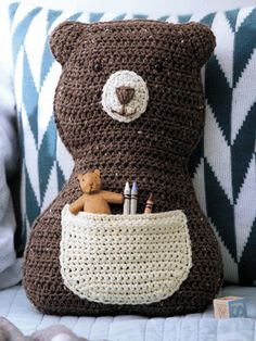 a crocheted teddy bear sitting on top of a pillow