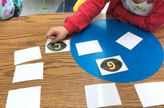 a young child is sitting at a table with paper cut out to make a circle