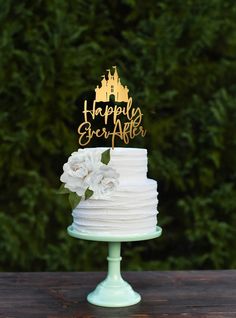 a white cake topped with a gold happy birthday cake topper on a wooden table