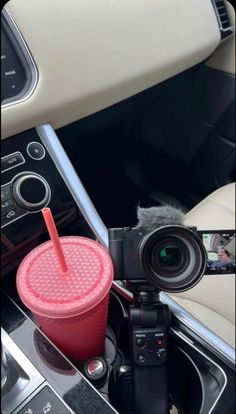 a car dashboard with a camera and a drink in the cup on top of it