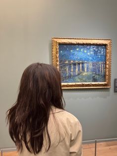 a woman looking at a painting on display