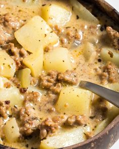 a wooden bowl filled with meat and potatoes