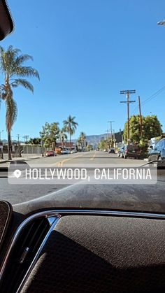 the view from inside a car looking at palm trees and cars driving down the road