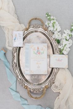 a silver plate with some white flowers on top of it and baby's breath cards