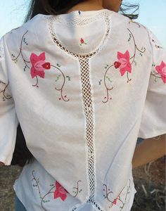 Tie front blouse in white with hand embroidered floral details and crochet panels. V neckline. Short sleeve. Ties to front. Size M, EU 38-42 / UK 10-14. Measurements: 40"/ 102cm bust - 12" / 30cm sleeve length - 25" / 64cm blouse length. Condition - New. Material - Cotton. Sustainability - Remade by our in house team using vintage fabrics. Model is a UK 6/8 & 5'7" tall. Bohemian Broderie Anglaise Short Sleeve Blouse, Bohemian Blouse With Broderie Anglaise Short Sleeves, Short Sleeve Blouse With Lace Work For Spring, White Short Sleeve Blouse With Lace Work, Short Sleeve Lace Blouse For Spring, White Lace Work Blouse With Short Sleeves, Bohemian Short Sleeve Blouse With Lace Work, Bohemian Short Sleeve Lace Blouse, White Crochet Top With Floral Embroidery For Summer