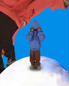 a small child standing on top of a snow covered ground next to an adult's foot