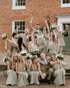 a group of people standing next to each other in front of a brick building holding bouquets