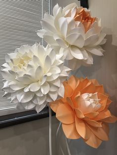 three white and orange paper flowers in a vase