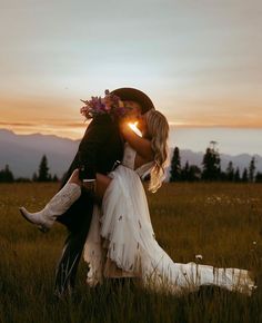 a bride and groom kissing in a field at sunset