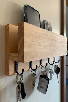 a wooden shelf with keys and cell phones hanging on it's hooks in front of a mirror