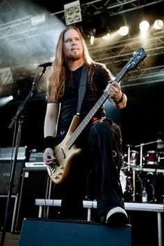 a man with long hair playing guitar on stage