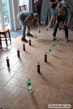 a group of people standing in a room with bottles on the floor and one person holding a baseball bat