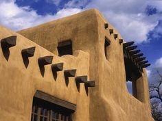 an adobe - style building with arched windows against a cloudy blue sky