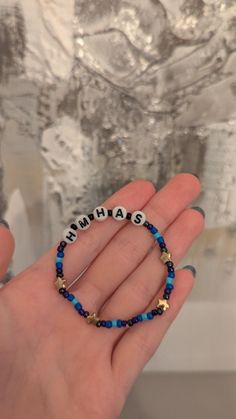 a person holding a beaded bracelet with the words hannah on it in front of a silver background