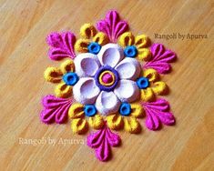 a close up of a flower made out of fabric on a wooden surface with the words ranggol by apurra written below it