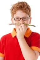 a boy with glasses is holding a pencil in his mouth