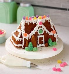 a gingerbread house on a plate with sprinkles and icing next to it