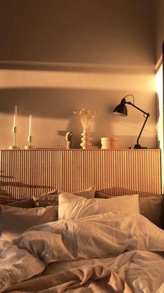 an unmade bed with white sheets and two lamps on the headboard in front of it