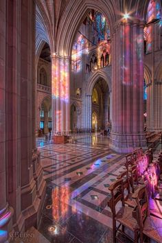 the inside of a cathedral with stained glass windows and benches in front of an alter