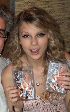 a man and woman holding up two small dvd's in front of their faces