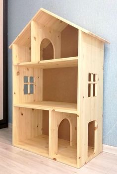 a wooden doll house sitting on top of a hard wood floor next to a blue wall