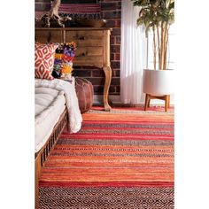 a bedroom with brick walls and colorful rugs on the floor, along with a bed