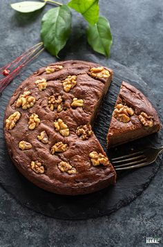 a chocolate cake with walnuts on top and a slice cut out from it next to a fork