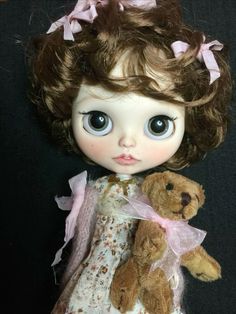 a close up of a doll holding a teddy bear