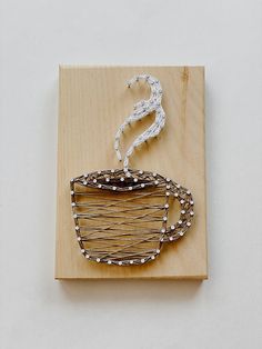 a piece of art made out of wood and wire with a coffee cup on it