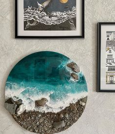 two framed pictures hang on the wall next to a table with rocks and water in it