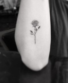 a black and white photo of a rose tattoo on the left upper half of the arm