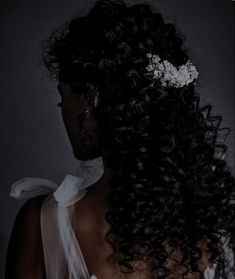 the back of a woman's head with curly hair and a flower in her hair