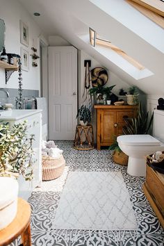 a bathroom with a white toilet sitting next to a bath tub under a slanted roof