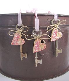 three heart shaped keys are attached to the handle of a brown suitcase with pink bows