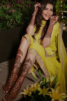 a woman sitting on top of a chair next to flowers and holding her hands up