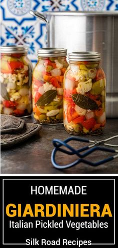 three jars filled with pickled vegetables sit on a counter