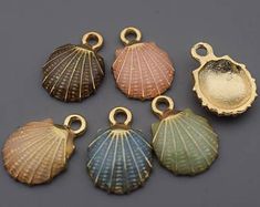 six seashell charms in various colors on a gray background, including one shell and the other