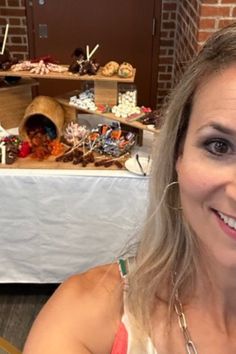 a woman is smiling for the camera in front of a table full of desserts