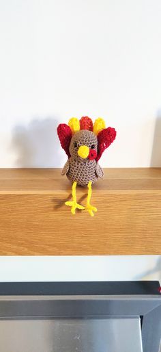 a knitted turkey sitting on top of a counter next to a microwave oven door