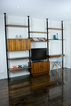 a living room with wooden floors and shelving unit