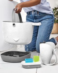 a woman is pouring water into a pot on the floor with other items around her