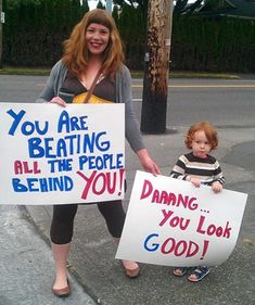 a woman and child holding up signs on the side of the road that read, you are beating all the people behind you