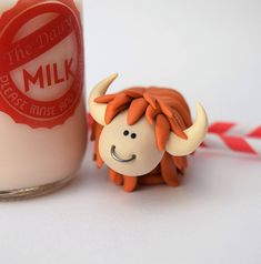 a glass jar with a red and white label next to a small toy cow that is sitting in front of it